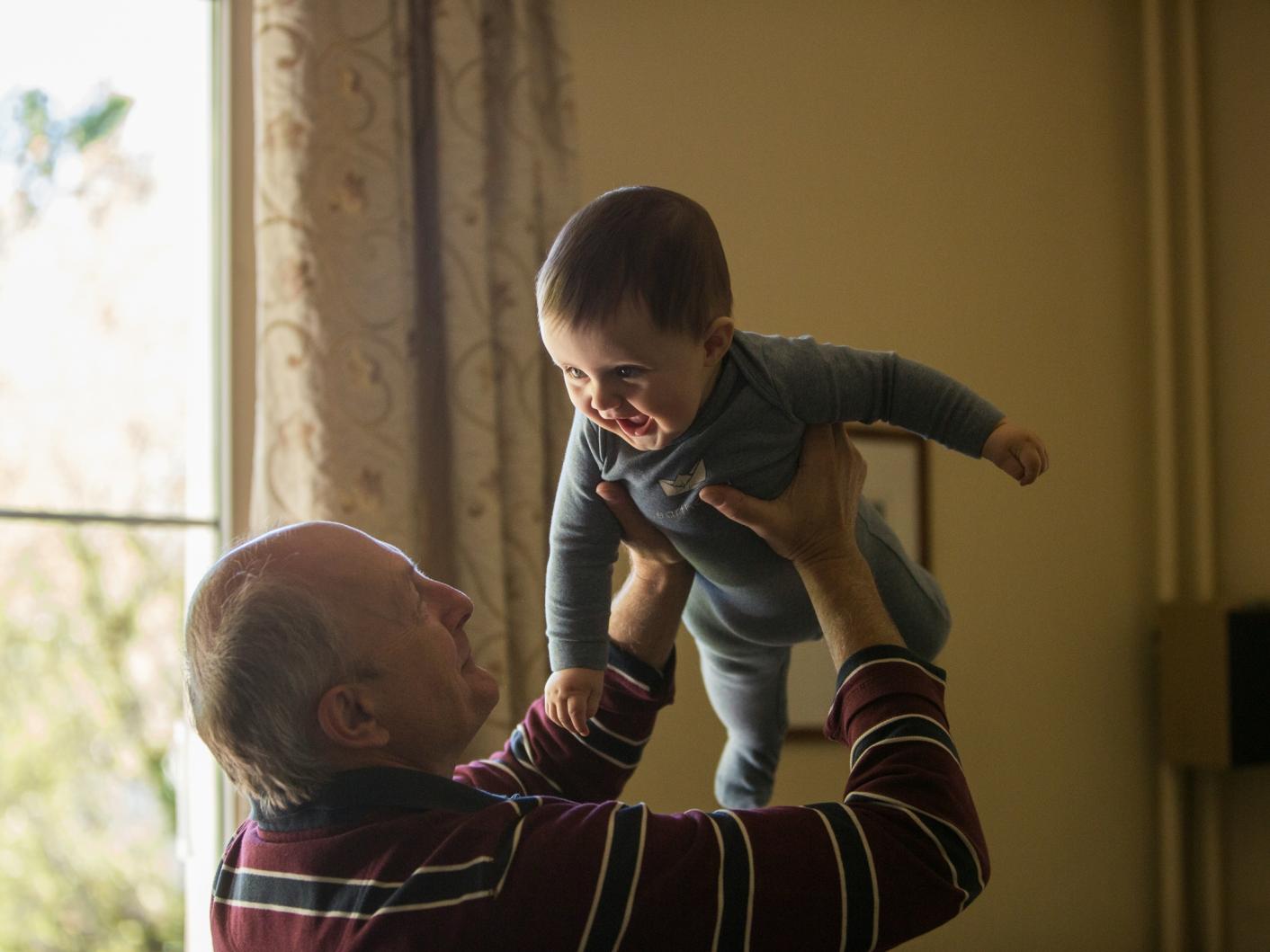 Older man holding a baby in the air