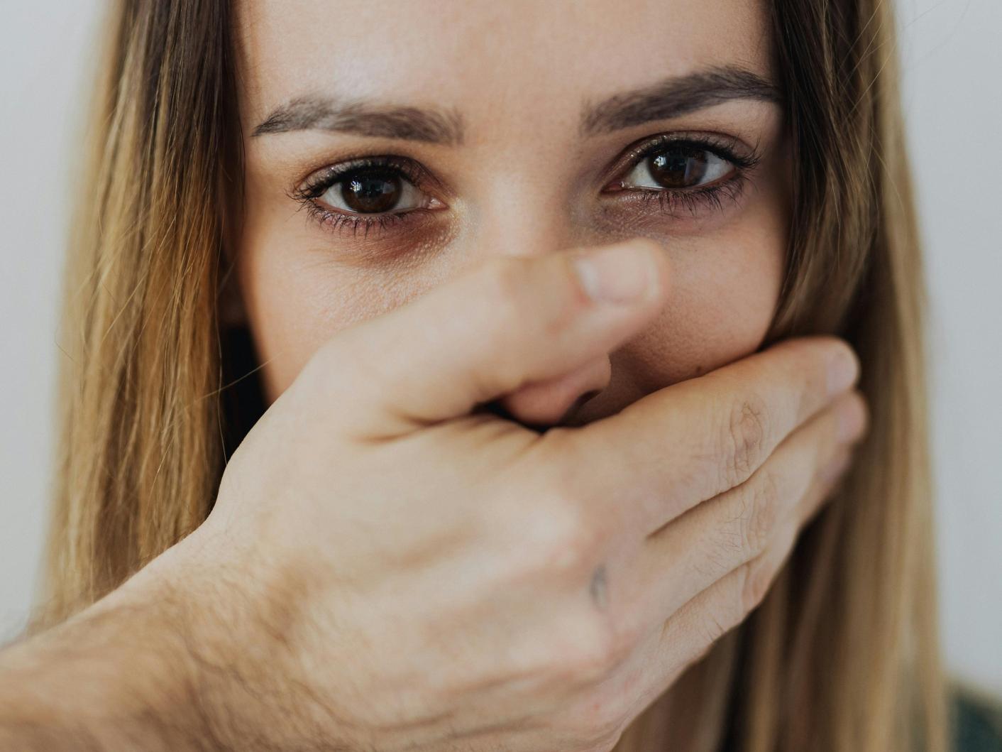 Hand of a man covering the mouth of a woman