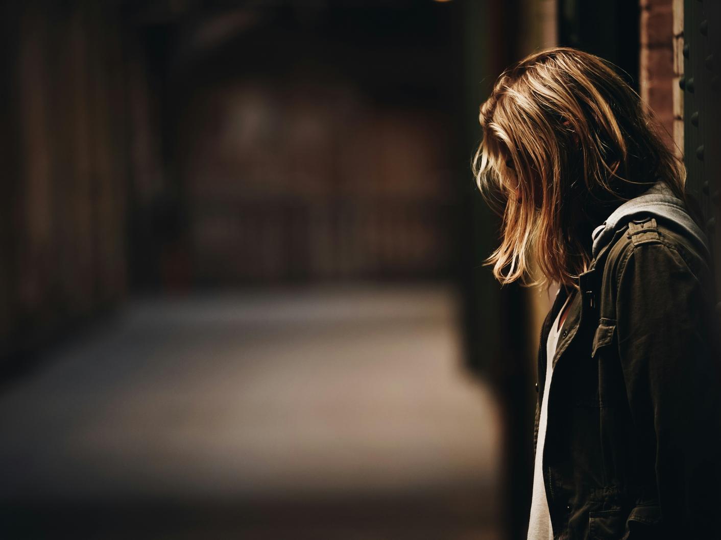 Girl standing against a wall looking upset