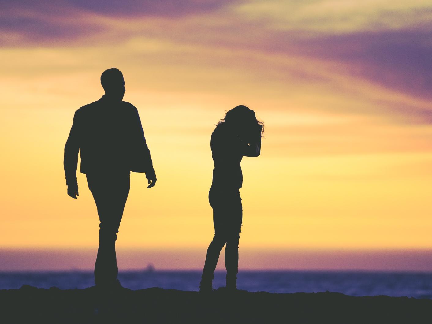 Silhouette of couple walking on a beach at sunset