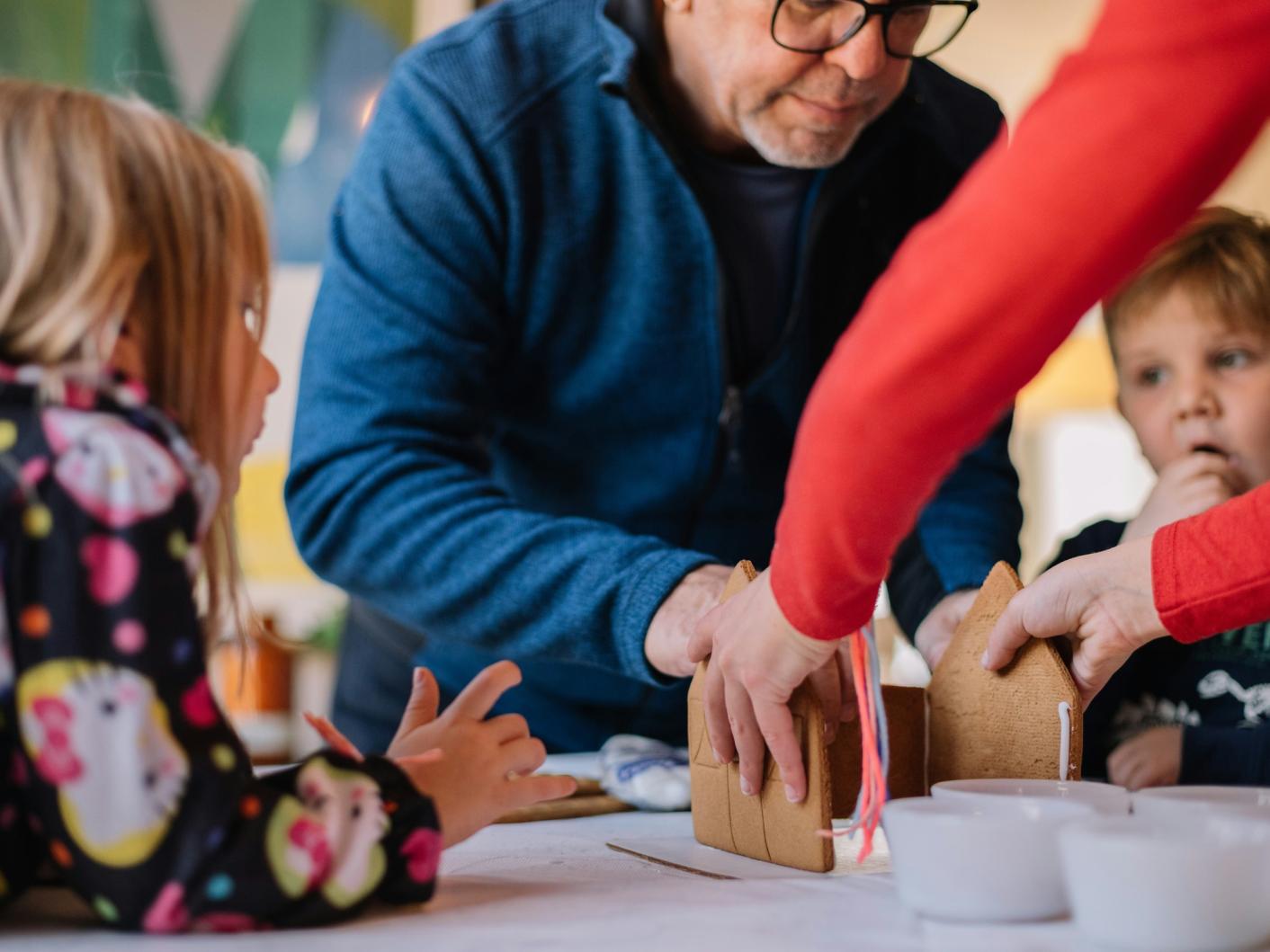 Grandparents making a gingerbread house with grandchildren